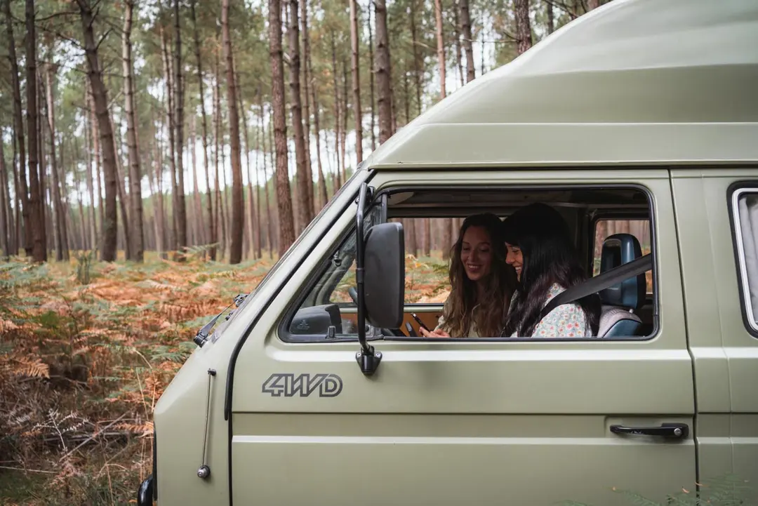 Deux amies dans leur van consultant un téléphone en forêt